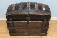 Front view of large antique sea chest showing curved top, metal straps, and lock.