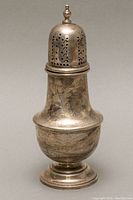Side view of the sterling silver sugar shaker showing engraved floral patterns and domed perforated lid with finial.