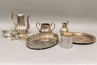 Group view of silver plated tea set, vanity set and serving trays, showing overall condition and contents.