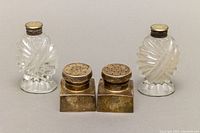 Full view of four shakers, two crystal with sterling silver/mother of pearl lids and two small square metal shakers.