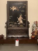 Full front view of wooden frame with black lacquer panel showing goddess inlays and carved base