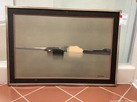 Front view of framed art print showing abstract landscape in muted tones, silver metal frame with black and pink mat, signature visible