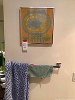 Needlepoint art hanging on wall above two towels on a towel bar