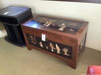 Overall view of wooden trunk with black enamel panels and metal latch
