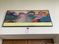 Frontal wide view of the entire framed print hanging on a wall above a room entrance showing the size and framing.