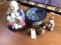 Overview of large Buddha statue, cloisonné bowl, covered boxes, and Pueblo storyteller figurine on table