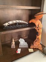 Shelf overview showing all four sculptures: elephant arch, eagle, Buddha, glass lovers