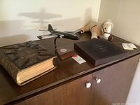 Front shelf showing wooden-bound Bible, USAF model plane, coffee table book