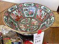 Top view of large painted porcelain bowl showing detailed colorful floral and figure paintings inside the bowl.