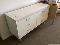 Full view of the white painted dresser showing six drawers arranged in two columns with metal handles. It stands on tapered legs and measures approximately 29 x 54 x 18 inches.
