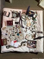Overhead view of entire lot on white cloth showing necklaces, bangles, rings, cufflinks, brooches, watches