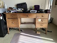 Front view of desk with items on top and light brown finish