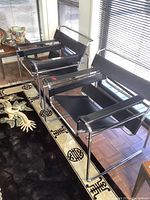 Three chairs side by side on a patterned rug near windows