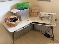 Corner sewing table set up with Viking machine, woven boxes and wicker basket