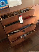 Wooden dresser drawers open showing drawers with flatware and linens