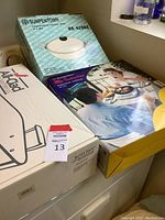 Overview of all boxed items showing the Sunpentown stainless steel pot, All-Clad roti pan, and Sunpentown induction cooktop boxes.