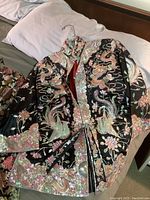 Black embroidered jacket laid flat on bed