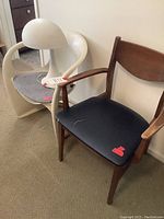 Wooden chair, plastic chair, and table lamp displayed together