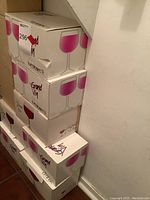 Stack of six unopened Luminarc Grand Vin wine glass boxes against a wall.