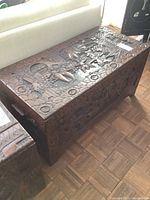 Angled view of carved wooden trunk on parquet floor