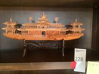 Intricately carved wooden ship measuring about 10 x 18 inches displayed on an ornate stand
