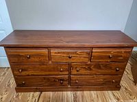 Front view of the large wooden dresser showing all 7 drawers and wooden knobs.