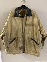 Outback Workwear men's jacket hanging on black hanger, tan color with leather collar and zip closure, front view