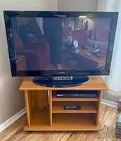 Samsung 42-inch plasma TV placed on wooden stand with BluRay player and remotes visible.
