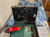 Overall view of open metal case with tools and accessories inside.