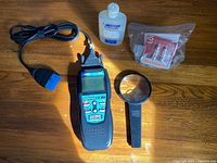 Photo showing the diagnostic tool, magnifying glass, cleaning fluid, and small parts on wooden surface.