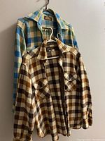 Front view of two vintage Eddie Bauer wool jackets in plaid, showing full front, collars, chest pockets, and button closures.