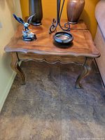 Photo showing one of two brown wooden end tables with curved cabriole-style legs and decorative scalloped apron and edge.