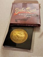 Photo of front side of Babe Ruth collectible coin housed in plastic sleeve and black holder, with visible embossed image and signature of Babe Ruth.