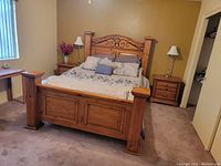 Full view of wooden bed set including headboard, footboard, mattress, box spring and two nightstands