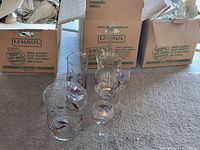 Photo of all glassware items arranged on carpet with boxes in background, showing multiple stemmed glasses, large bowl, and pitcher