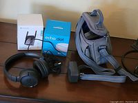 Full lot arranged on table including Rock Space WiFi extender box, Amazon Echo Dot box, JBL wired headphones, and gray-blue fabric carrying bag.