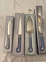 Four Wedgwood Blue Jasper cutting devices in original boxes, handles visible with blue jasperware and stainless blades covered in plastic.
