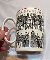 Photo showing close-up of Wedgwood mug held by hand, depicting detailed black and white illustrations of English monarchs in historic costumes, with commemorative text around top edge.