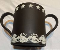 Black two-handled loving cup showing star motif and floral wreath band