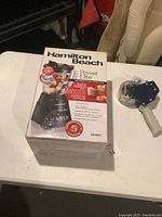 Blender box and unit including jar filled with fruit pieces to show blender capacity and function. Box highlights 12 blending functions, 5 year warranty, and dishwasher safe jar.