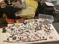 Overview of the entire jewelry lot showing multiple pieces spread out on a white cloth including necklaces, bracelets, rings, earrings, and a wristwatch.