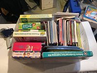 Box with several kids learning kits and educational books arranged and stacked on the table.