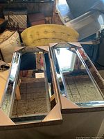 Two boxed new mirrors side by side in a room with furniture and storage bins visible.