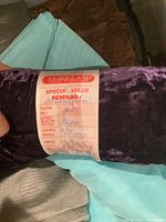 Close-up of a purple crushed velvet bolt with Fabricland remnant label showing price and length
