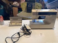 Full view of Kenmore sewing machine with foot pedal and accessory box on a white table.