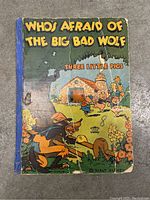 Front cover showing colorful illustration of Big Bad Wolf and Three Little Pigs house with wear and spine tape.
