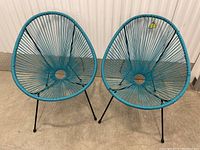 Front view of two blue patio egg chairs with circular metal center and woven blue string seat and back