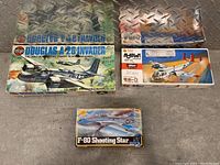 Three boxed vintage model kits of aircraft and helicopter on a metal background.