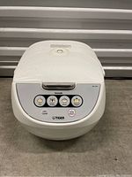 Front view of the white Tiger Tecook electric rice cooker model JBV-A10U showing control panel with function buttons.