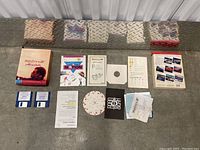 Overview of all items including box, floppy disks, manuals, paper wheel, and printed sheets.